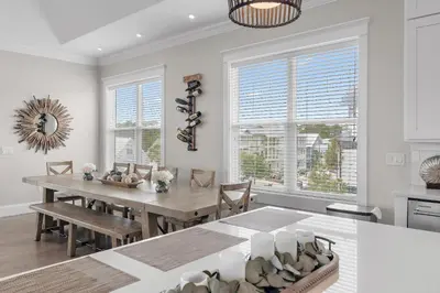 a dining room with a table and chairs and windows at Buena Vista in Santa Rosa Beach