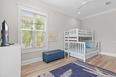 a room with a crib and a chair and a window at Buena Vista in Santa Rosa Beach
