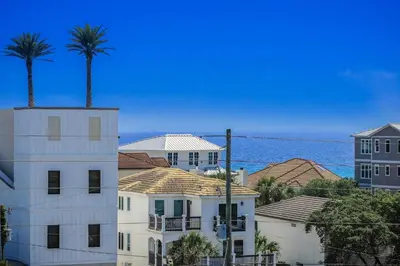 a building with palm trees and the ocean in the background at Buena Vista in Santa Rosa Beach