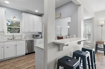 a kitchen with white cabinets and stools in it at Caribbean Breeze in Seacrest