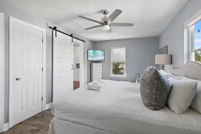 a bedroom with a white bed with a ceiling fan at Caribbean Breeze in Seacrest