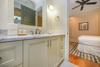a bathroom with a sink and a bedroom at Hidden Cypress in Santa Rosa Beach