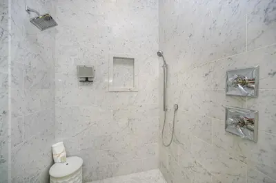 a white bathroom with a shower and a toilet at Hidden Cypress in Santa Rosa Beach
