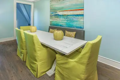 a dining room with a table and yellow chairs at Mercado at Rosemary 4A in Rosemary Beach