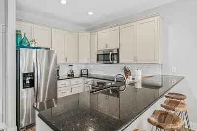 a kitchen with white cabinets and a stainless steel refrigerator at Edge of the Sea in Seacrest