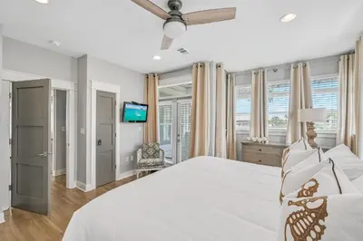 a bedroom with a white bed and a tv at Edge of the Sea in Seacrest