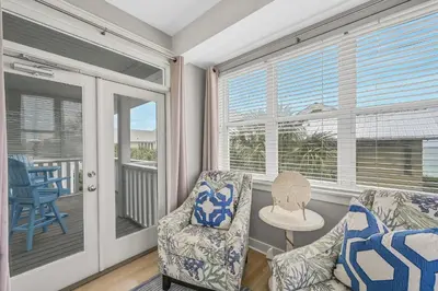 a screened in porch with two chairs and a table at Edge of the Sea in Seacrest