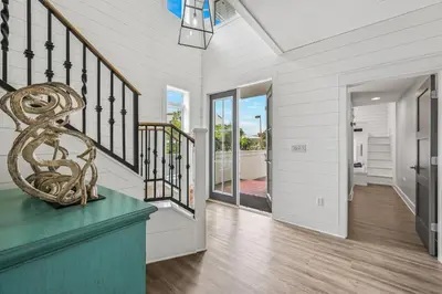 a home with a staircase and aoyer with white walls at Edge of the Sea in Seacrest