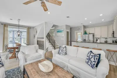a living room with two white couches and a kitchen at Edge of the Sea in Seacrest