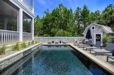 a swimming pool with chairs and a house at 172 A Street in Inlet Beach