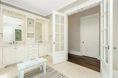 a white bathroom with two sinks and a bench at 172 A Street in Inlet Beach