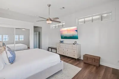a white bedroom with a bed and a ceiling fan at Sandy Boardwalk in Santa Rosa Beach