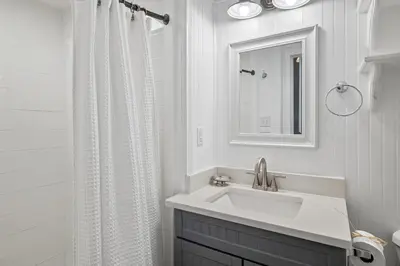 a white bathroom with a sink and a mirror at Sandy Boardwalk in Santa Rosa Beach