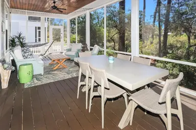 a screened porch with a white table and chairs at Paradise Found in Santa Rosa Beach