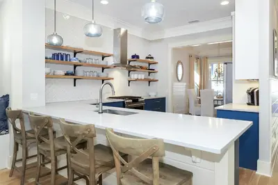 a kitchen with a large white counter and chairs at Paradise Found in Santa Rosa Beach