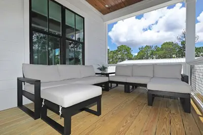 a porch with two white couches and a window at Sonshine by the Sea in Santa Rosa Beach
