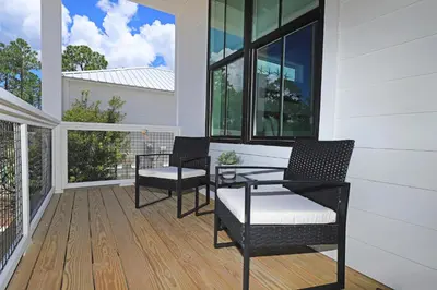 a screened porch with two chairs and a table on it at Sonshine by the Sea in Santa Rosa Beach