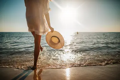 a woman walking on the beach with a straw hat at Sea-Rest in Inlet Beach