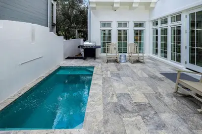 a swimming pool on a patio with a house at Harp's Haven Main and Carriage in Inlet Beach