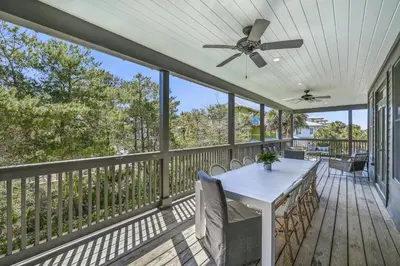 a screened porch with a ceiling fan and a table at 48 Geoff Wilder in Inlet Beach