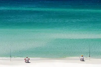 two people sitting on the beach with fishing rods at 48 Geoff Wilder in Inlet Beach