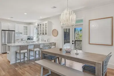 a kitchen with white cabinets and a dining table at 48 Geoff Wilder in Inlet Beach