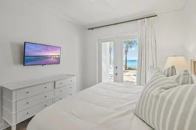 a white bedroom with a bed and a window with the ocean at Sunsational in Santa Rosa Beach