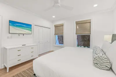 a white bedroom with a bed and a tv at Sunsational in Santa Rosa Beach