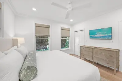a white bedroom with a bed and a dresser at Sunsational in Santa Rosa Beach