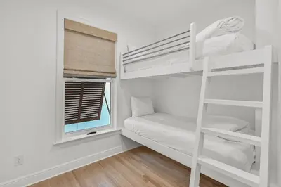 a white bedroom with bunk beds and a window at Sunsational in Santa Rosa Beach