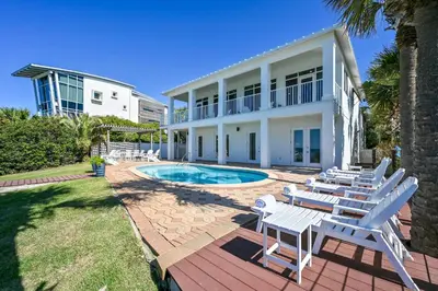 a villa with a swimming pool and lounge chairs at Sunsational in Santa Rosa Beach