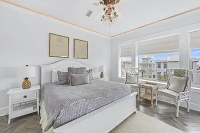 a white bedroom with a bed and a chair at 15 Mathis Cove in Inlet Beach