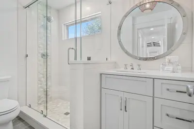 a white bathroom with a shower and a sink and a mirror at 105 Pelican Circle in Inlet Beach