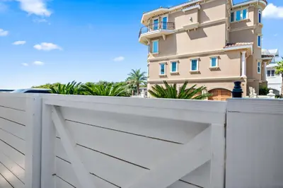a white fence with a house in the background at Sunset Lounge in Santa Rosa Beach