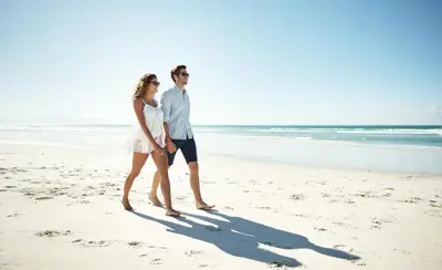 a man and a woman walking on the beach at Sunset Lounge in Santa Rosa Beach