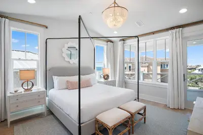 a bedroom with a bed and windows and a chandelier at Sunset Lounge in Santa Rosa Beach