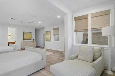 a white bedroom with a bed and a chair at 239 Pelican Circle in Inlet Beach