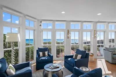 a living room with blue furniture and large windows at The Flying Pig in Santa Rosa Beach