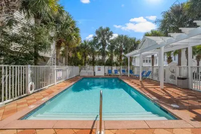 a swimming pool with a fence and palm trees at The Flying Pig in Santa Rosa Beach