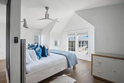 a white bedroom with a bed with blue pillows at 34 S Briland Lane Carriage House in Rosemary Beach