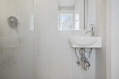 a bathroom with a shower with a sink and a mirror at 34 S Briland Lane Carriage House in Rosemary Beach