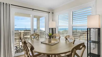 a dining room with a table and chairs and a balcony at Eastern Shores 103 in Santa Rosa Beach