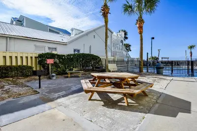 a picnic table in front of a building with palm trees at Sunbird 102E By Book That Condo in Panama City Beach