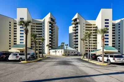 a parking lot with palm trees and tall buildings at Sunbird 102E By Book That Condo in Panama City Beach