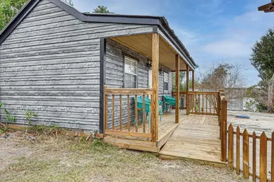 a cabin with a wooden deck with a chair on it at Lakefront Panama City Studio with Hot Tub Access in Panama City