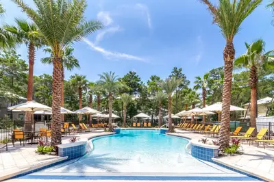 a pool with chairs and palm trees at the resort at 30A Magnolia Cottages by the Sea by Panhandle Getaways in Seacrest