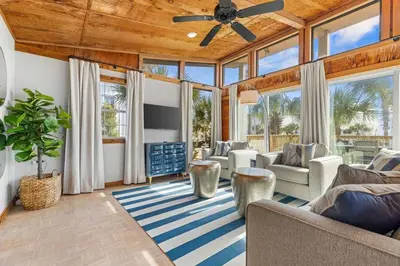 a living room with a ceiling fan and large windows at Dry Dock in Seagrove Beach
