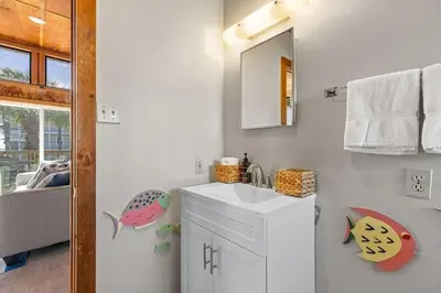 a white bathroom with a sink and a mirror at Dry Dock in Seagrove Beach