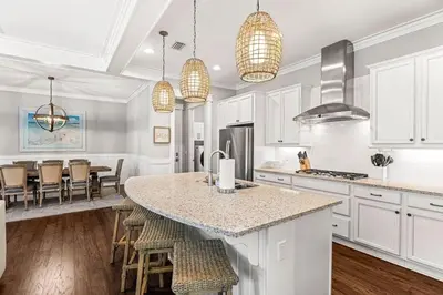 a kitchen with white cabinets and a table with stools at Nature and the Beach in Santa Rosa Beach