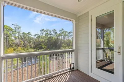 a balcony with a large window and a view of the woods at Nature and the Beach in Santa Rosa Beach